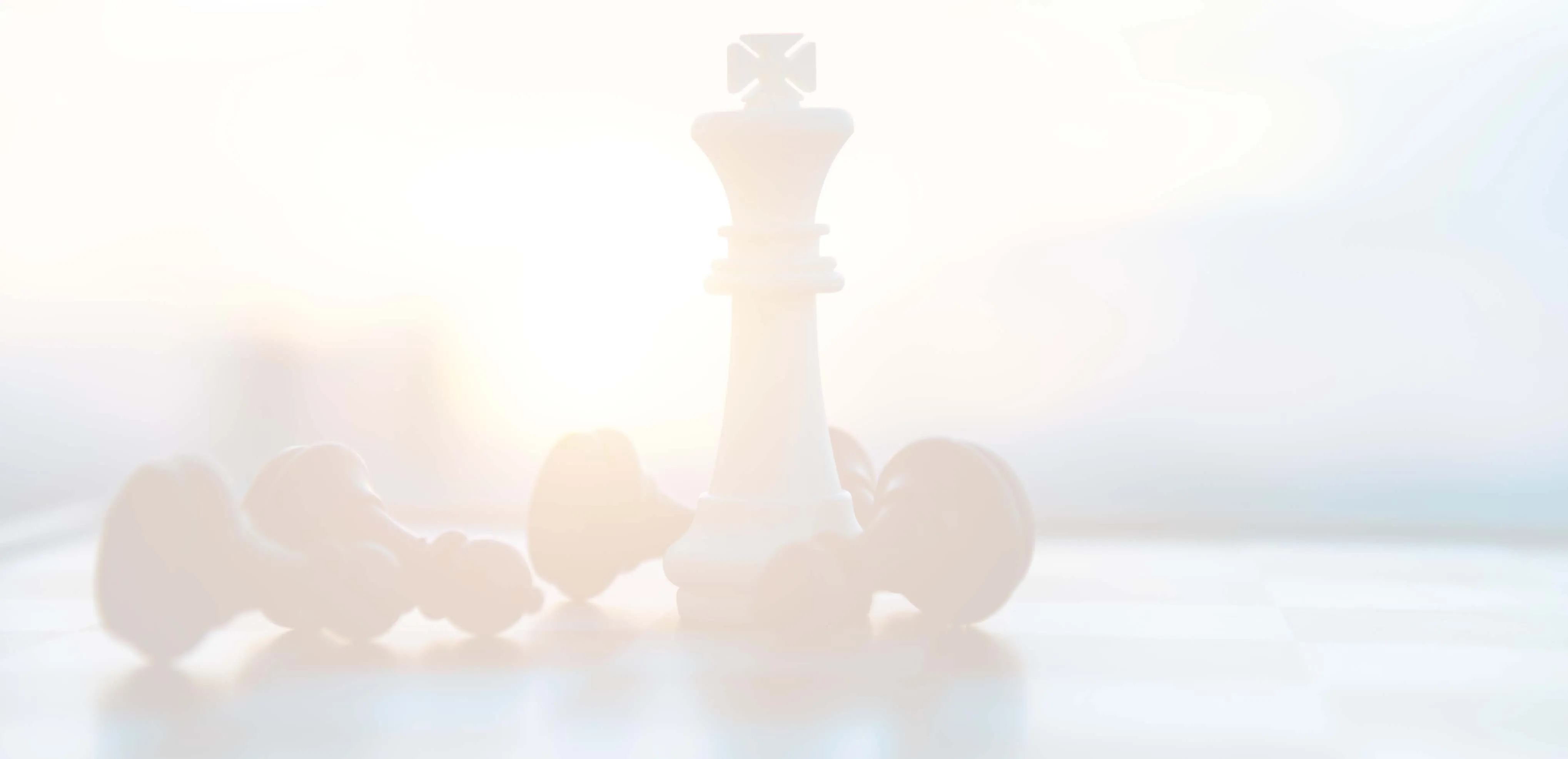 A white chess king on a chessboard, surrounded by fallen black pawns. The setting sun in back is casting a warm glow.